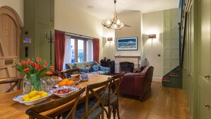 Een eetruimte met een houten tafel, stoelen, een vaas tulpen en een fruitschaal.