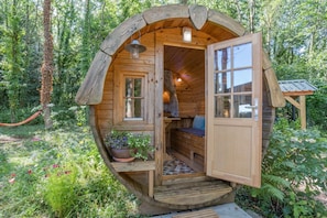 A wooden cabin with a large open door, a window, and a small porch area. - 2 Bed in Whitecastle (oc-f32639) (Abergavenny)