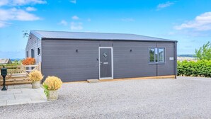A modern building with a grey exterior, a wooden door, and a small window. - 2 Bed in Somerton (oc-s32606) (Windy Ridge)