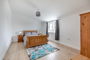 Ein Schlafzimmer mit einem hölzernen Bett, Nachttischen, einem Schrank und einem Fenster mit Vorhängen.