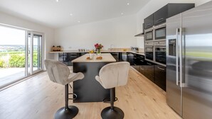 A modern kitchen with a central island, stainless steel appliances, and a large window offering a view of the outdoors. - 2 Bed in Somerton (oc-s32606) (Windy Ridge)