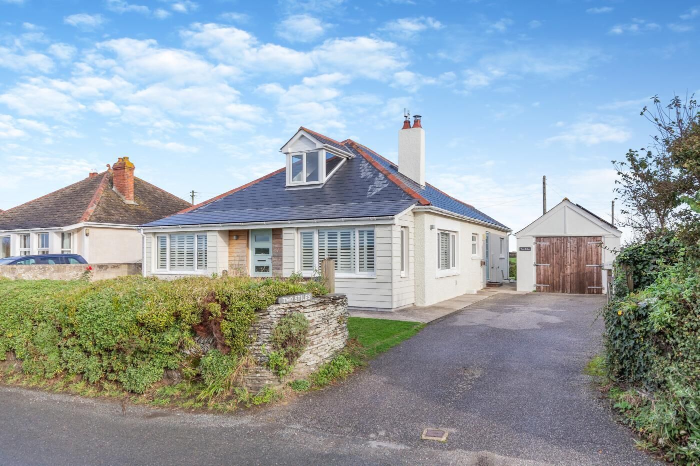 Une maison à deux étages, dotée d’un toit en pente, d’une cheminée et d’un garage.