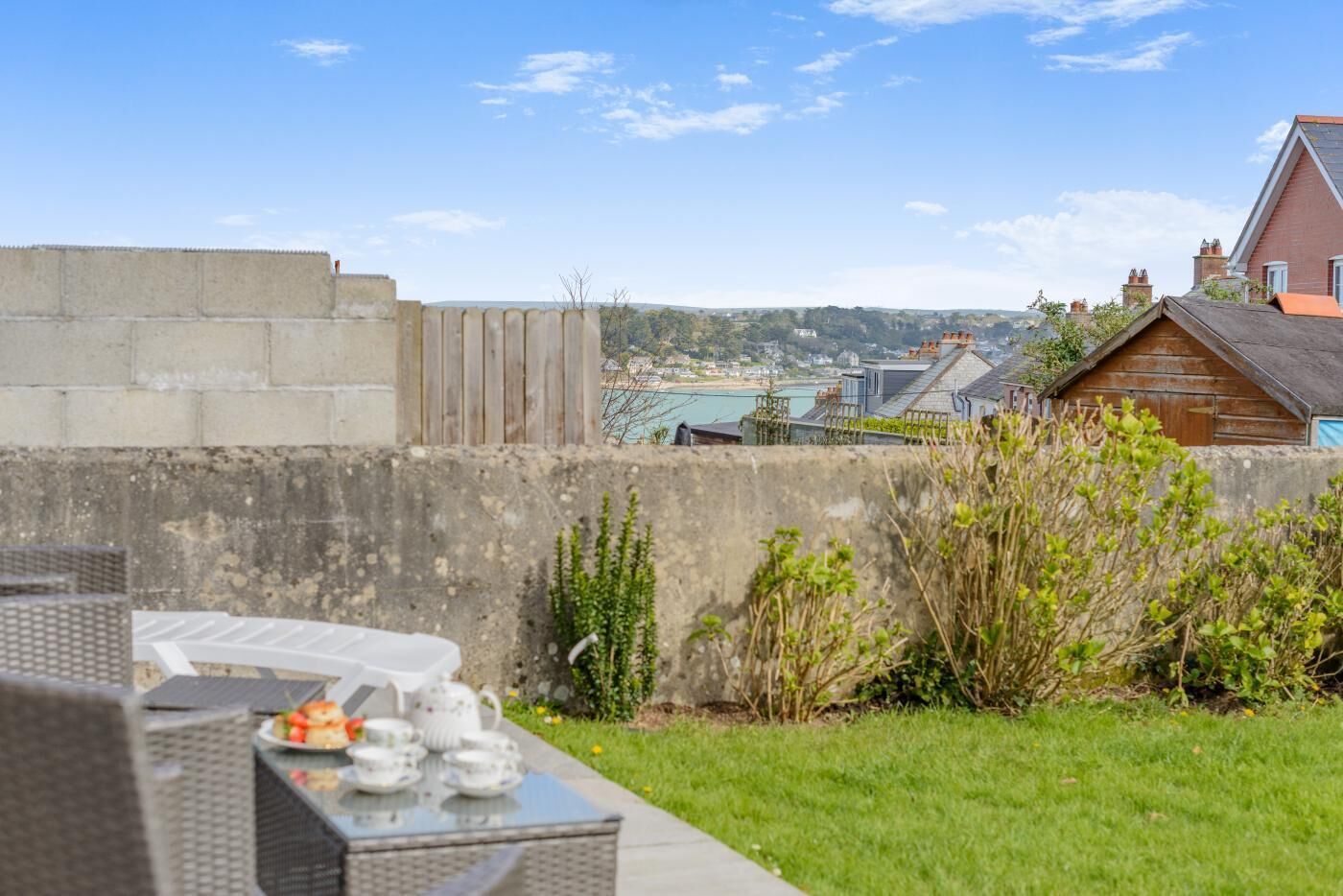 A patio with outdoor furniture, a view of the sea, and a distant town.