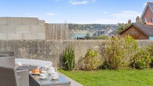 A patio with outdoor furniture, a view of the sea, and a distant town. - 3 Bed in Padstow (oc-p00878) (Padstow)