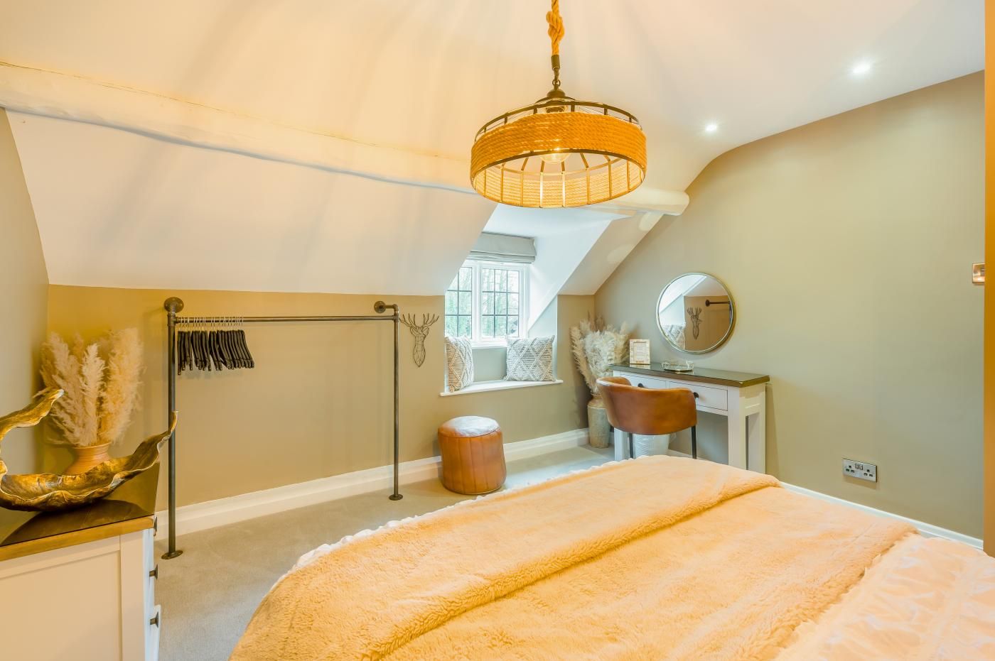 A bedroom with a large bed, a desk, a chair, a mirror, and a window.