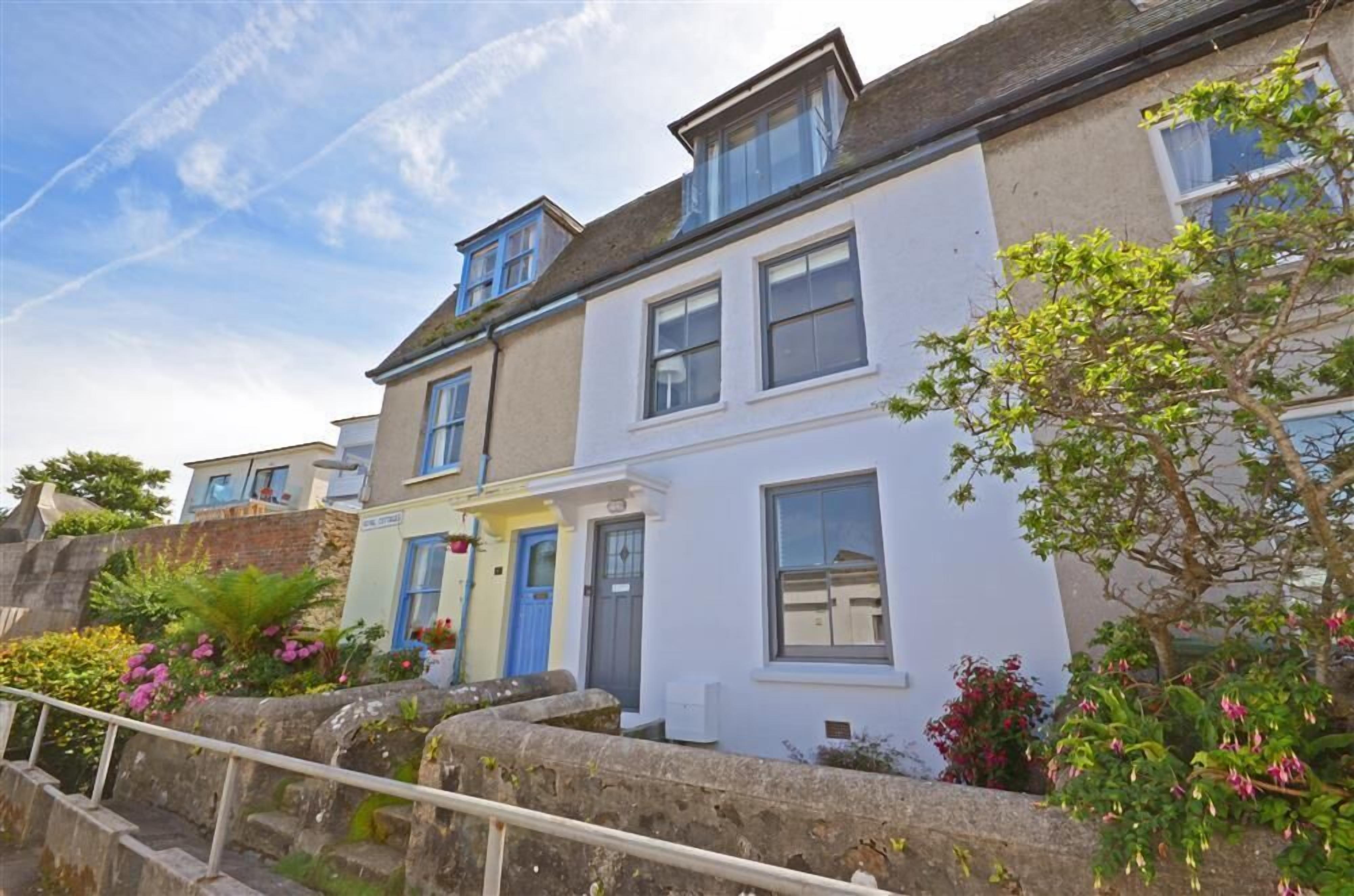 A row of terraced houses with a stone staircase leading up to a gated entrance.