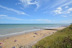 A beach with a wooden pier extending into the sea, sandy shore, and grassy areas. - 5 Bed in Sidestrand (oc-bize) (Trimingham)