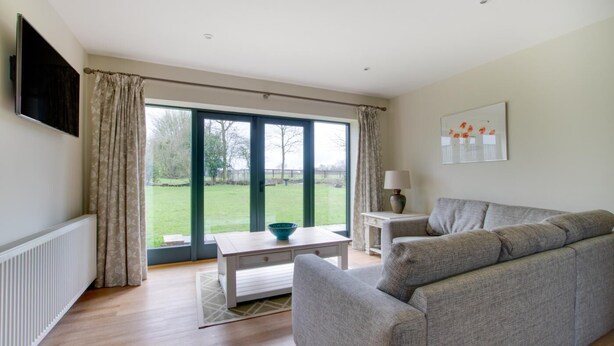 A modern living room with a grey sofa, a coffee table, and a TV mounted on the wall. - 2 Bed in Weybread (oc-tclwey) (Upper Weybread)
