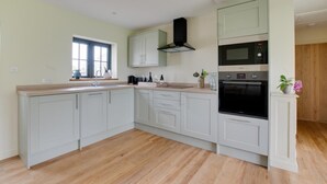 A modern kitchen with light-colored cabinets, a built-in oven, and a window providing natural light. - 2 Bed in Weybread (oc-tclwey) (Upper Weybread)