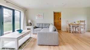 A modern living room with a grey sofa, a white coffee table, and a dining area with wooden chairs and a table. - 2 Bed in Weybread (oc-tclwey) (Upper Weybread)