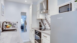 Una cocina moderna con armarios blancos, una campana extractora de acero inoxidable, un horno empotrado y un microondas.