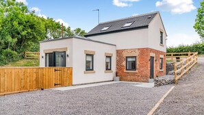 Een modern huis met twee verdiepingen, een losstaande garage, houten omheining en een grindpad.