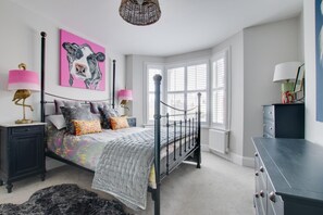 A bedroom with a bed, bedside tables, a dresser, a window, and a painting on the wall. - 5 Bed in Southwold (oc-tlw) (Southwold)