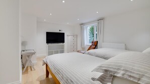 Ein Schlafzimmer mit Bett, Fernseher, Schreibtisch und Fenster.