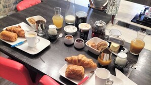 Een ontbijttafel met croissants, koffie en sap.