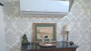 Een houten dressoir met een lijstfoto, een dienblad met glazen en een lamp op een marmeren aanrecht.