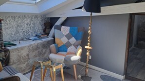 Een moderne leefruimte met dakraam, een gestreept fauteuil, een glazen salontafel en een vloerlamp.