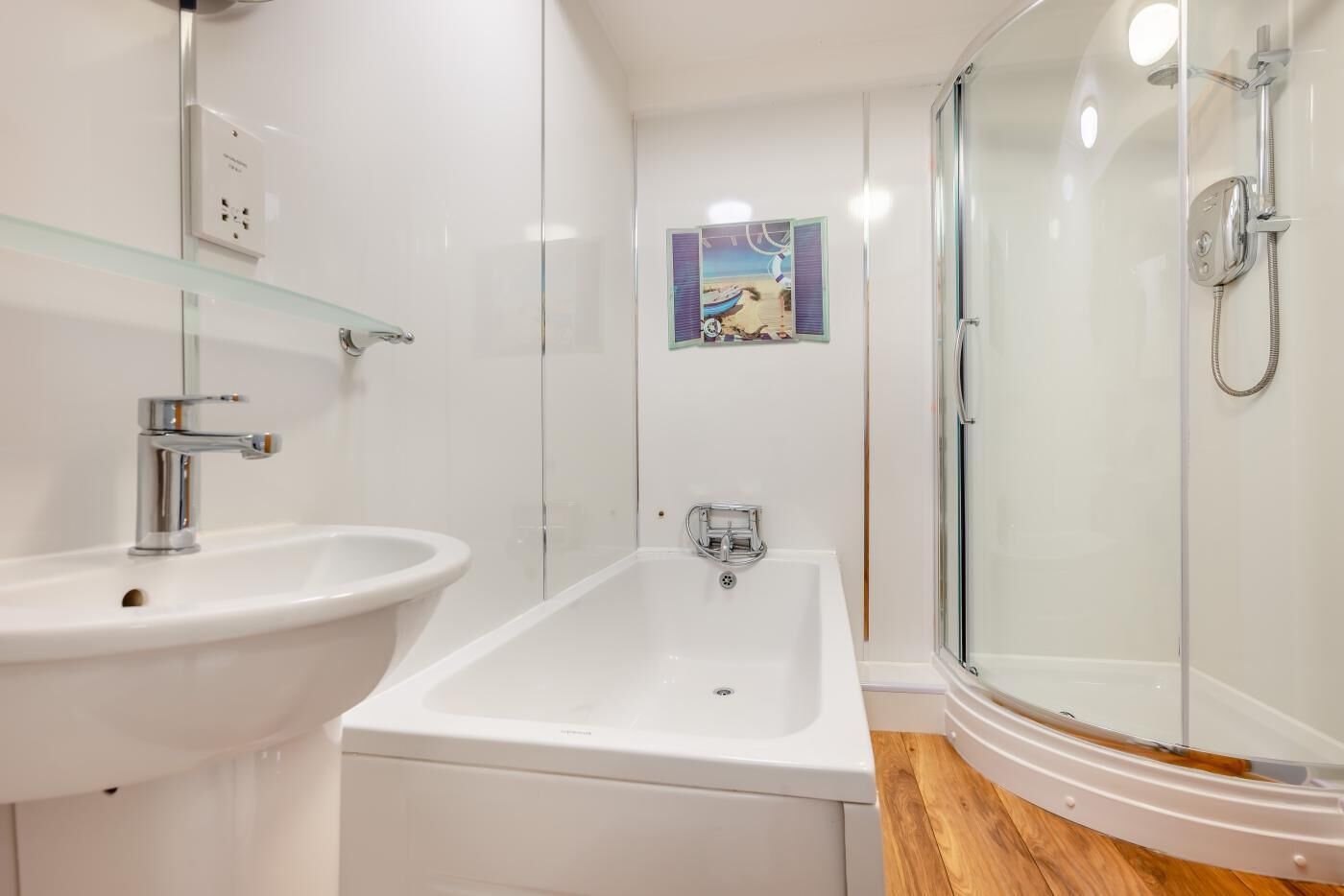 A modern bathroom with a white sink, a bathtub, and a glass-enclosed shower.