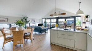 Una cocina amplia con comedor, ventanas grandes y vista al mar.