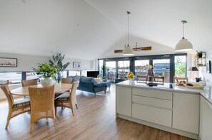 A spacious kitchen with a dining area, large windows, and a view of the sea.