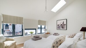 Un dormitorio moderno con una cama grande, una silla, un escritorio y un ventanal con vistas al exterior.