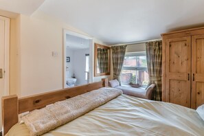 A bedroom with a wooden bed, a window with curtains, and a view of the outside. - 1 Bed in Middleton On The Wolds (oc-t32420) (Middleton-on-the-Wolds)
