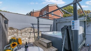 Een hottub met een houten terras en een stenen muur op de achtergrond.