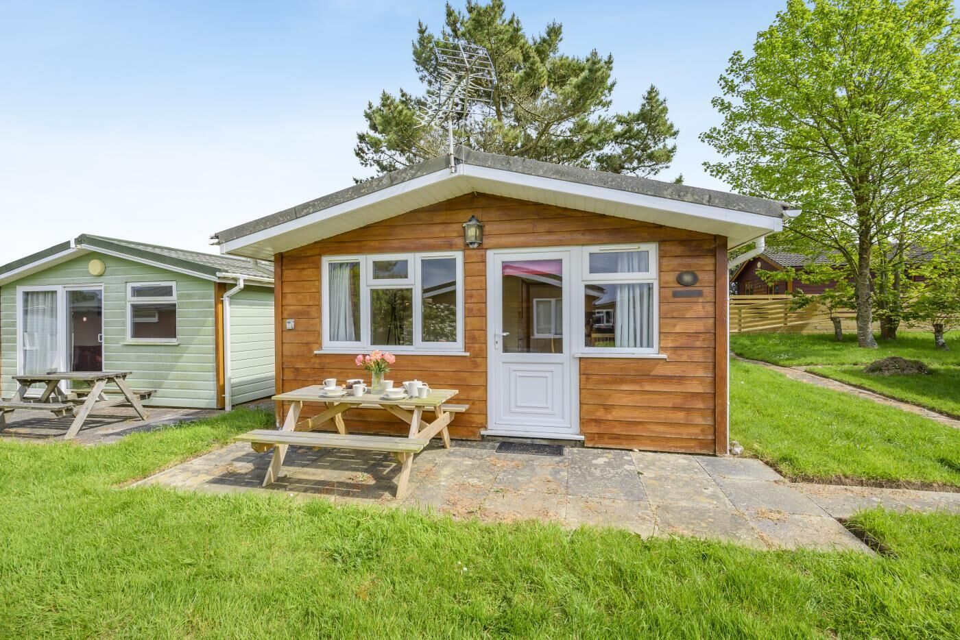 A small wooden cabin with a picnic table, a door, and windows.