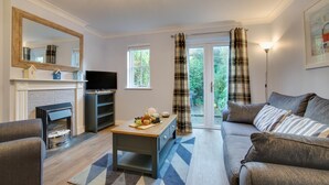 Ein modernes Wohnzimmer mit Kamin, Fernseher und einer Couch.
