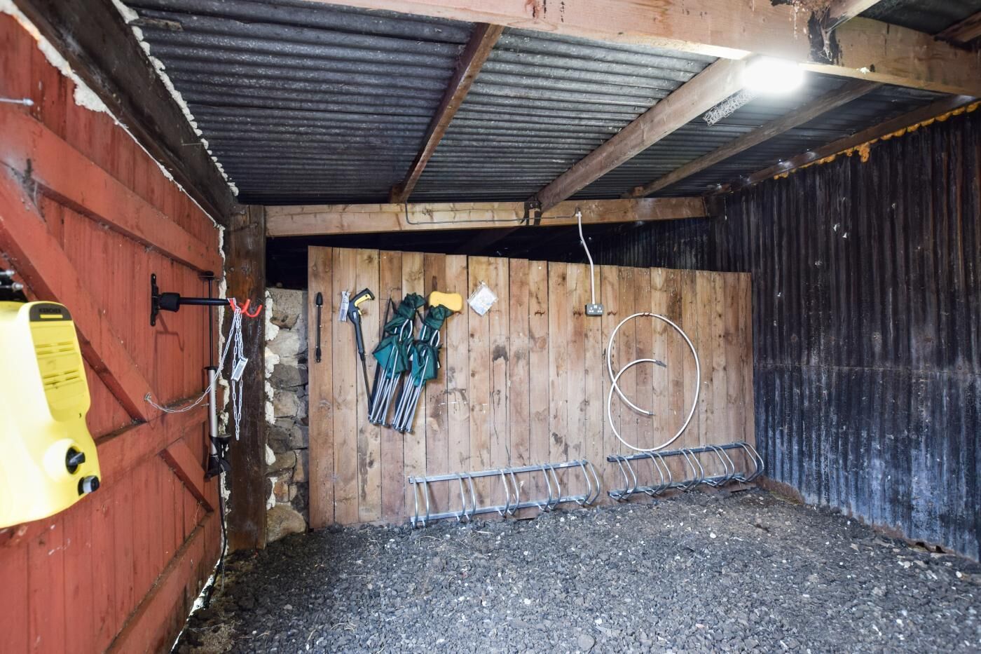 L’intérieur d’une grange rustique, avec un plancher en bois, des étagères en métal et un générateur jaune.