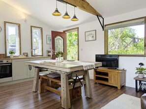 A kitchen with wooden flooring, a dining table, a TV, and large windows with greenery outside. - 1 Bed in Lawnhead (oc-w32576) (Gnosall)