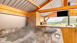 Un bain à remous dans un chalet en bois avec vue sur l’extérieur.