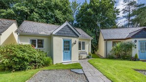 Une maison à deux étages avec une porte bleue, un petit porche et une allée gravillonnée.