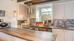 Una cocina moderna con encimera de madera, electrodomésticos de acero inoxidable y un ventanal que proporciona luz natural.
