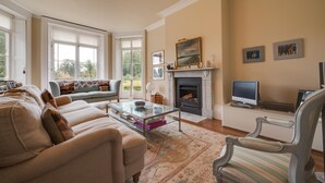 Een woonkamer met een open haard, bank en televisie.