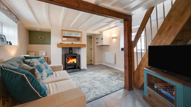 A cozy living room with a fireplace, a sofa, a television, and a staircase. - 1 Bed in Bodham (oc-2141) (Bodham)
