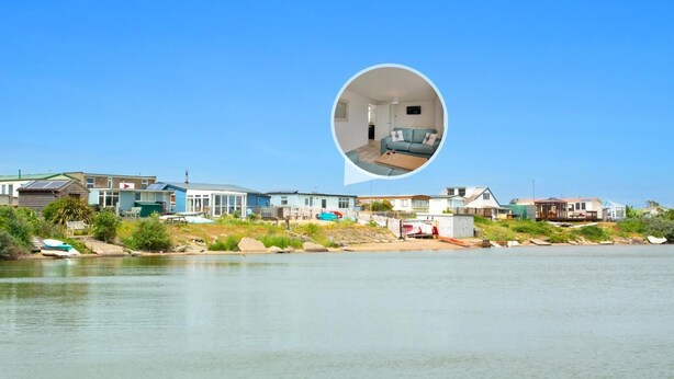 Una zona residenziale sul lungomare, con case affacciate sull'acqua, cielo sereno e una vista ingrandita di una stanza con divano e tavolino.