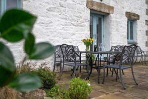 An outdoor seating area with a table and chairs, a vase with flowers, and a bottle of wine. - 3 Bed in Newbridge (oc-p00869) (Newbridge)
