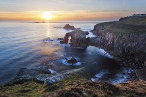 A coastal landscape with a prominent rock formation and a sunset over the sea. - 3 Bed in Newbridge (oc-p00869) (Newbridge)