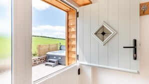 A room with a wooden door, a window, and a view of a green field. - 1 Bed in Umberleigh (oc-f32531) (Chittlehampton)