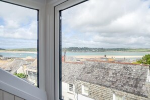 Blick vom Fenster auf die Küste mit Strand, Gebäuden und einem Leuchtturm.