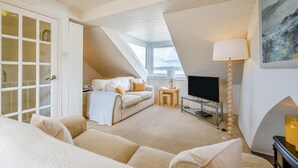 A cozy room with a sofa, a TV, a lamp, and a painting on the wall. - 4 Bed in Padstow (oc-p00245) (Padstow)