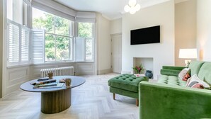 A room with a bay window, a fireplace, a green sofa, and a flat-screen TV mounted on the wall. - 3 Bed in Buxton (oc-p32528) (Buxton)