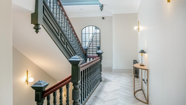 Un escalier avec une main courante en bois, des balustres noires et une balustrade en verre.