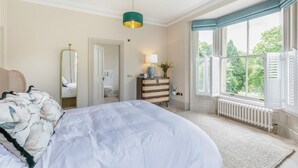 A bedroom with a large bed, a dresser, a mirror, a window with shutters, and a radiator. - 3 Bed in Buxton (oc-p32528) (Buxton)