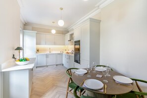 Une cuisine moderne avec des meubles blancs, une table à manger dressée avec des assiettes et des verres, et un sol décoré d’un motif en chevrons.