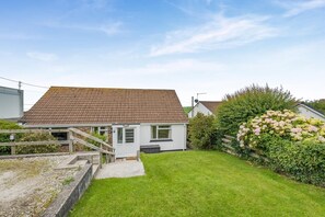 A single-story house with a tiled roof, a front porch, and a well-maintained lawn. - 4 Bed in Padstow (oc-p00401) (Trevone)