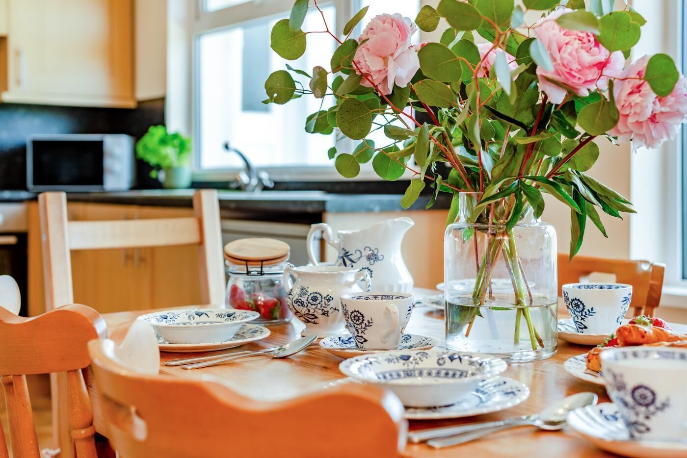 Une table à manger agrémentée d’un centre de table floral, d’un service à thé et d’assiettes.