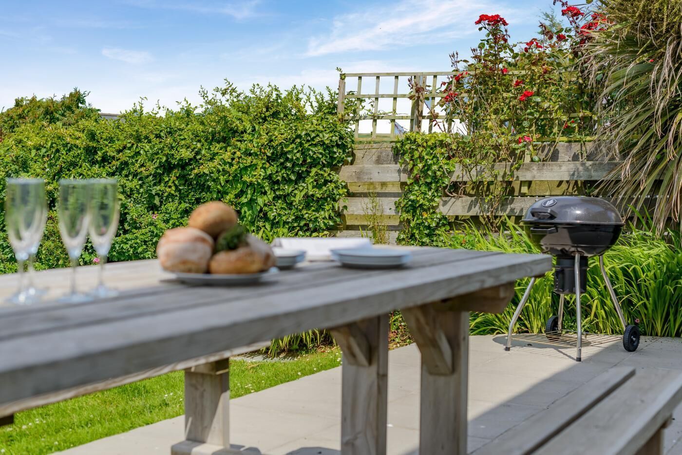 Une table de pique-nique en bois, avec des assiettes, des verres et du pain.