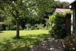 A garden with a pathway leading to a house with a red-tiled roof. - 2 Bed in Letheringsett (oc-endco) (Letheringsett)